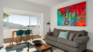 A modern living room with a gray sofa, a dining table with chairs, and a large abstract painting on the wall. - Jagar Court 8 (Cape Town)