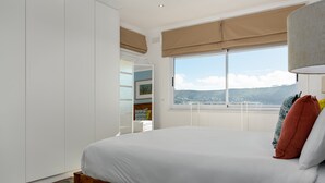 A bedroom with a large bed, a wardrobe, and a window with a view of the landscape. - Jagar Court 8 (Cape Town)