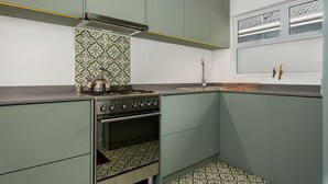 A kitchen with green cabinets, a stove, and patterned backsplash. - Jagar Court 8 (Cape Town)
