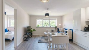 A modern kitchen with white cabinetry, a dining table, and a large window providing natural light.