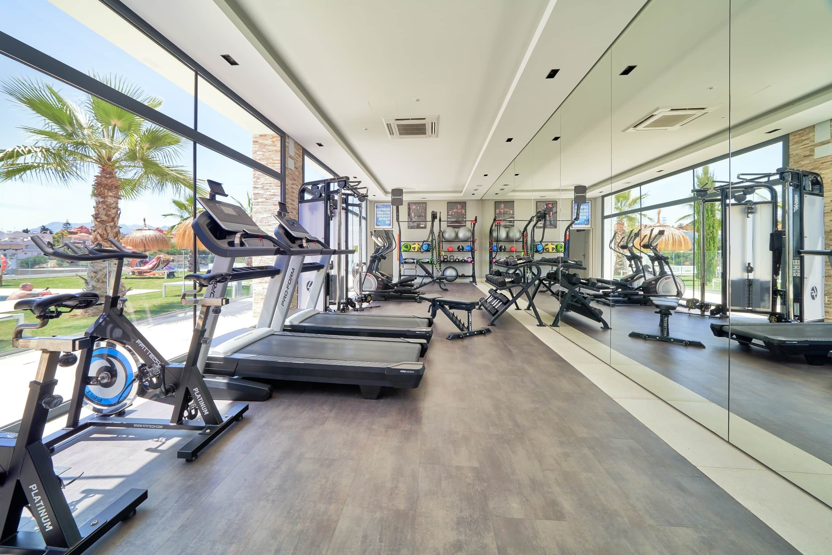 Une salle de sport moderne équipée de tapis de course, de vélos elliptiques et d’appareils de musculation.