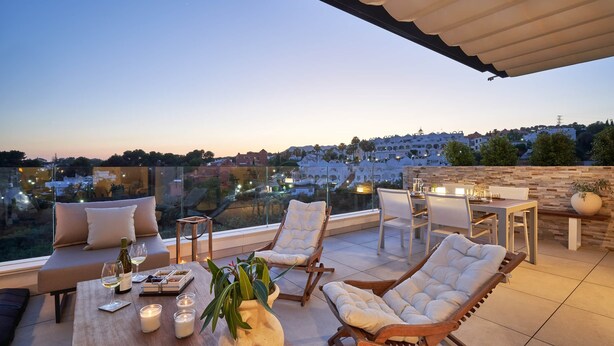 Terraço no terraço com um sofá, poltronas de descanso, uma mesa de jantar e velas.