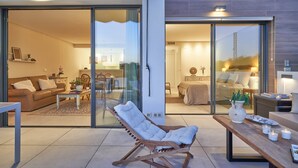 Uma sala de estar moderna com uma porta de vidro deslizante que dá para um quarto, uma cadeira de balanço de madeira e um espaço de jantar com velas.