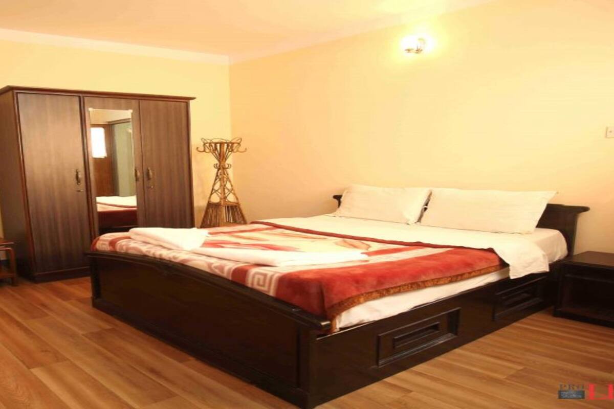 A bedroom with a bed, a wardrobe, a bedside table, and a lamp.