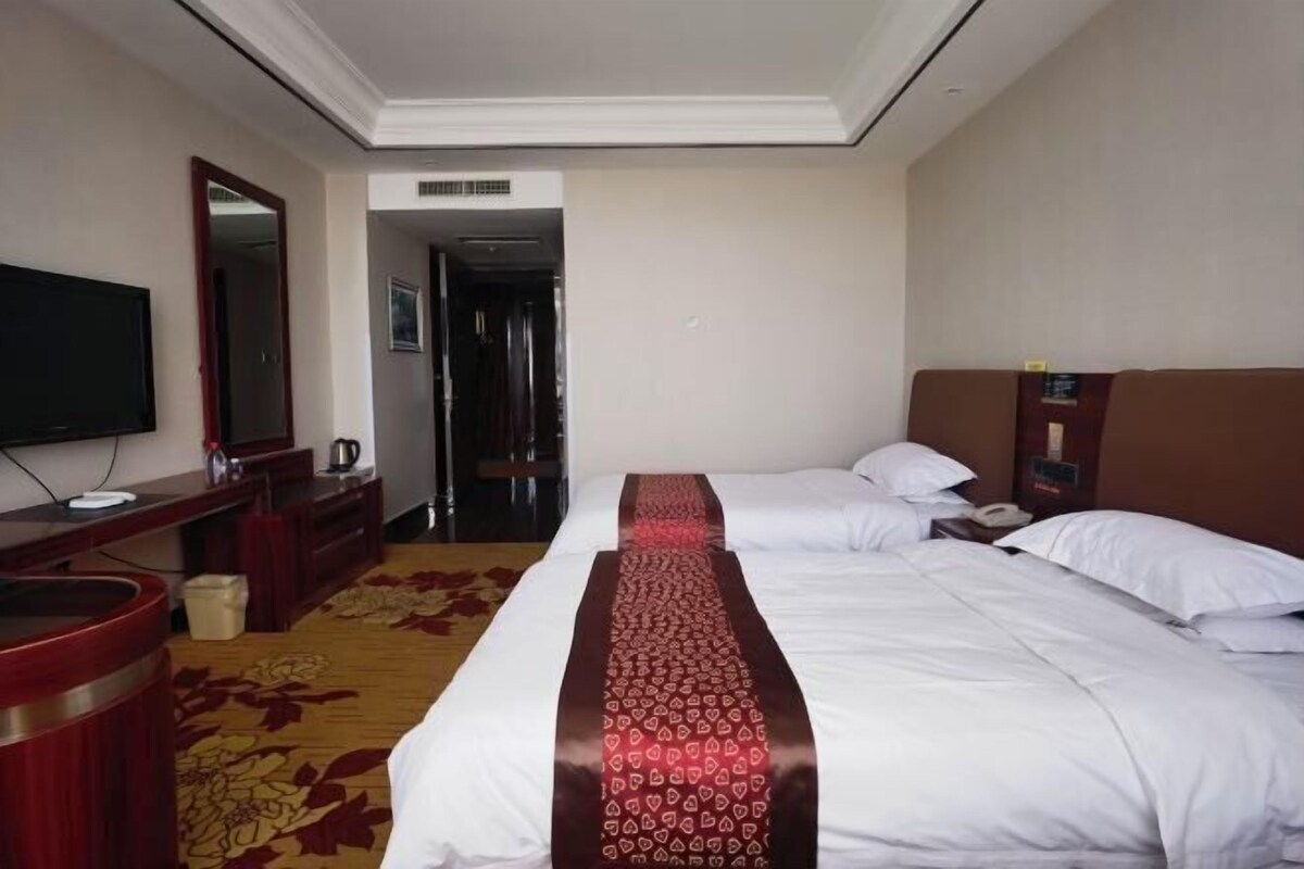 Une chambre d’hôtel avec deux lits, une télévision, un bureau et une salle de bain.