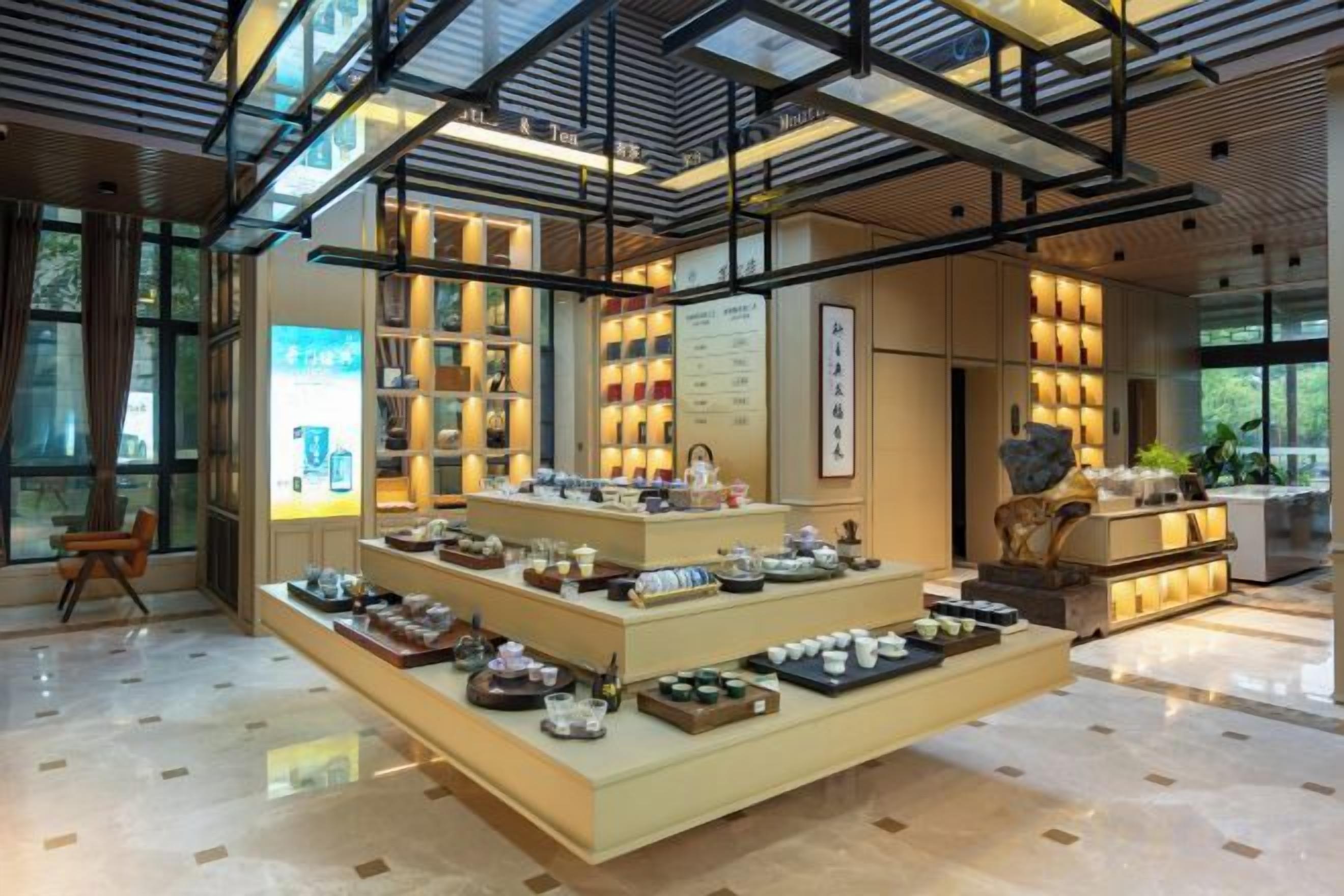 A modern interior with a central display of tea sets and a high ceiling with exposed beams.