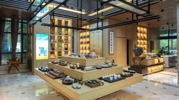 A modern interior with a central display of tea sets and a high ceiling with exposed beams.