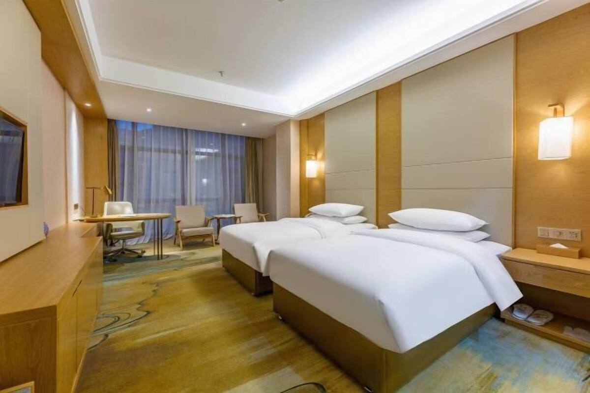 A hotel room with a large bed, bedside tables, a desk, and a chair.