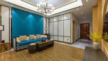 A modern living room with a blue sofa, a coffee table, and a chandelier.
