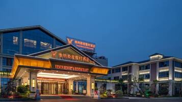 A modern hotel with a prominent entrance, signage for a restaurant, and a well-lit facade.