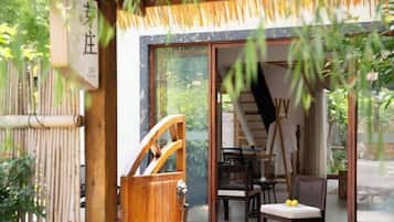 Quarto em estilo japonês tradicional, com esteiras de tatame, porta deslizante e vista para o jardim.
