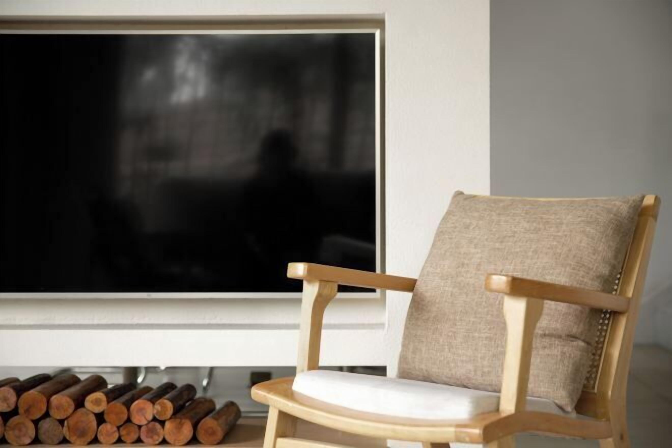 A wooden chair with a cushion and a television in front of it.