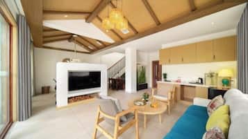 Uma sala de estar moderna com televisão, móveis de madeira, um sofá e uma área de cozinha com armários e uma mesa de jantar.