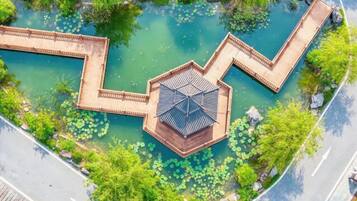 An aerial view of a park with a hexagonal pavilion and a winding water feature.