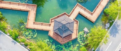 Vista aérea de un parque con un pabellón hexagonal y un canal de agua serpenteante.