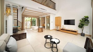 A spacious living room with a high ceiling, a staircase, a flat-screen TV, a wooden cabinet, and a potted plant. - Venus Resort (Yidu)