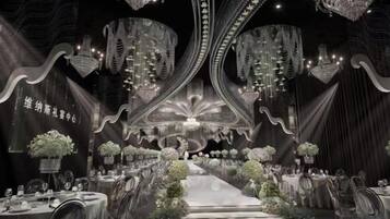 A formal event space with tables, chairs, and floral arrangements.