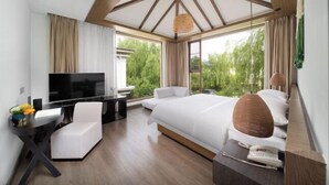 A modern hotel room with a large bed, a desk with a TV, a chair, and a view of greenery outside. - Venus Resort (Yidu)