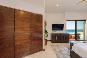 Quarto com um guarda-roupa espaçoso, televisão, planta e vista para o mar.