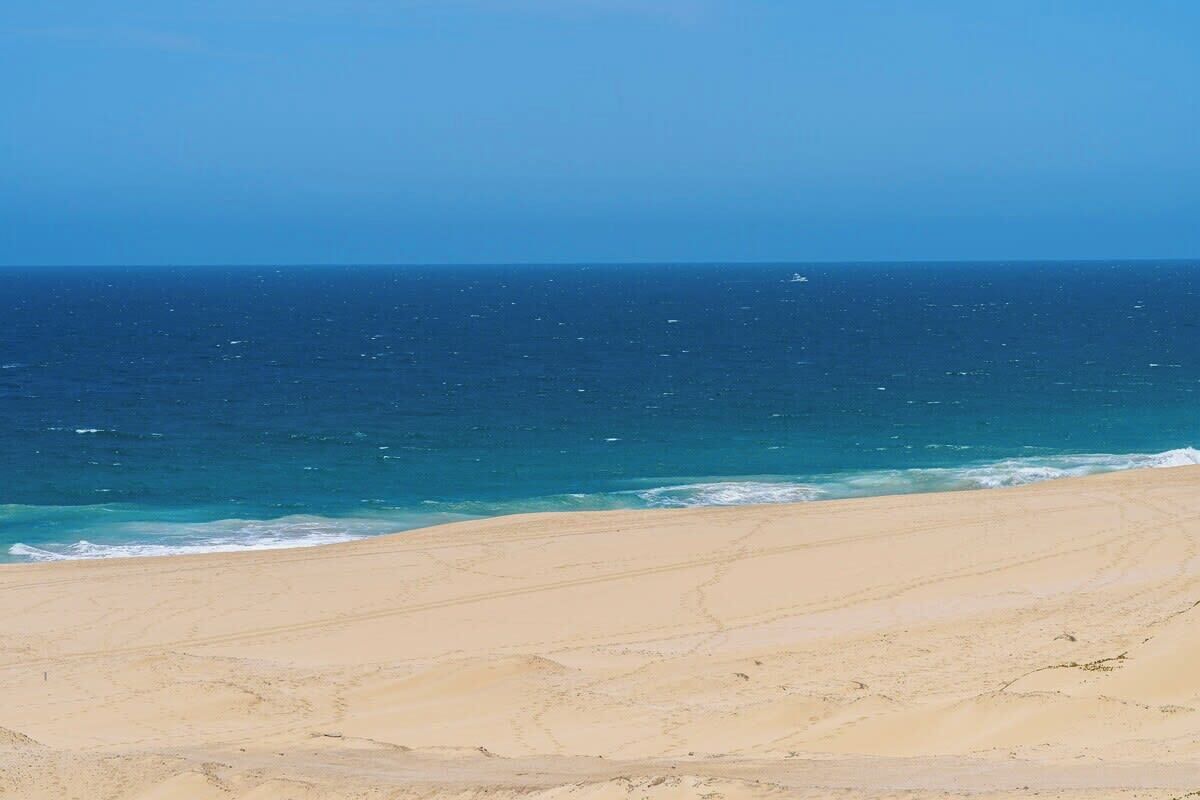 A beach with a clear view of the ocean and a sandy shore.