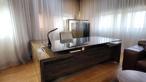 A modern office space with a glass desk, a chair, and a brown leather sofa. - Design Hotel Mr President (Belgrade)