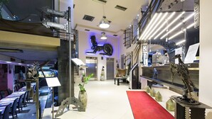 A modern hotel lobby with a red carpet, a staircase, and a dining area with tables and chairs. - Design Hotel Mr President (Belgrade)