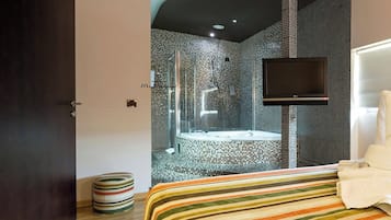Una habitación de hotel moderna con una cama grande, un televisor, zona de ducha y un diseño de pared original.
