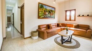 Ein geräumiges Wohnzimmer mit einem großen braunen Ledersofa, einem Couchtisch und einem Gemälde von Pferden an der Wand.