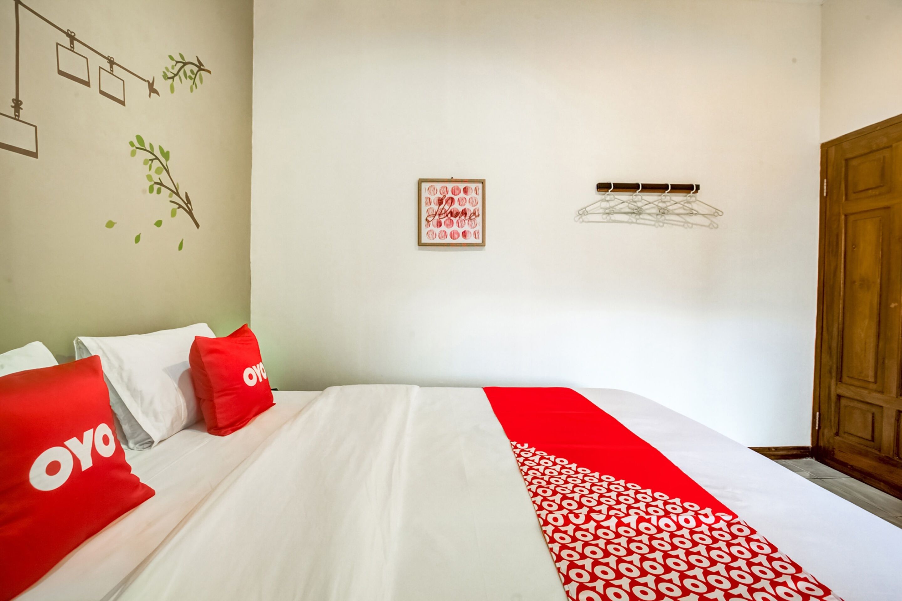 Quarto de hotel com cama bem arrumada, armário de madeira, quadro emoldurado na parede e um varal.