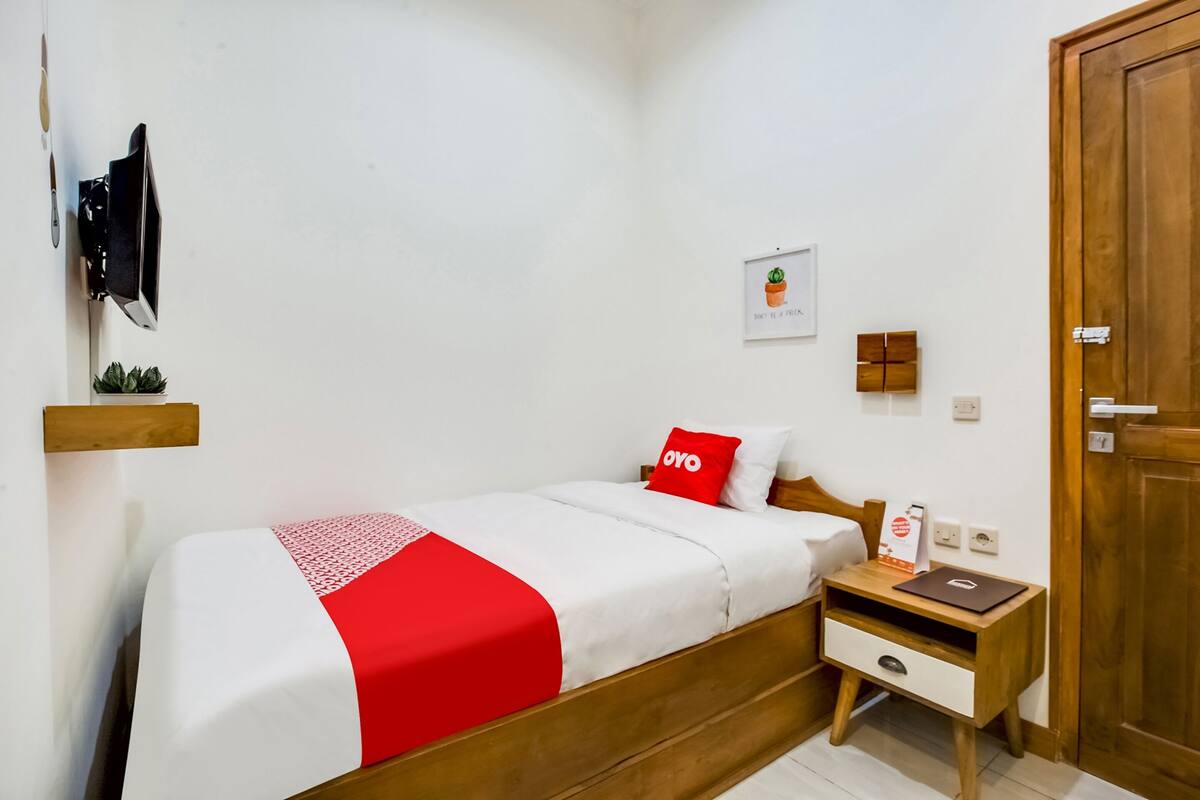 Ein ordentlich eingerichtetes Schlafzimmer mit Bett, Nachttisch und kleiner Ablage.