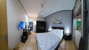 A bedroom with a bed, a desk, a TV, a wardrobe, and a window. - Maison Fifi (Drâa-Tafilalet)
