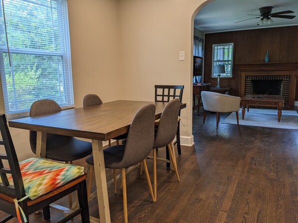 A dining area with a wooden table and chairs, a fireplace, and a view of the outdoors through a window.