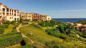 A resort with multiple-story buildings, a well-maintained garden, and a view of the sea. - Duplex with terrace and solarium, pool access and parking included (Saint-Raphaël)