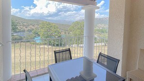 A covered outdoor seating area with a table and chairs, overlooking a mountainous landscape. - Duplex with terrace and solarium, pool access and parking included (Saint-Raphaël)