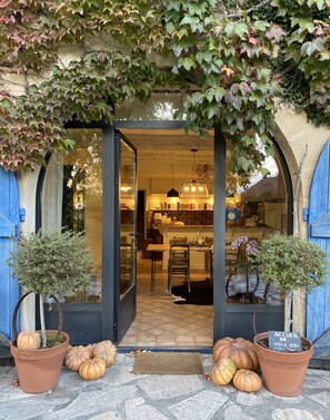 A rustic entrance with a wooden door, potted plants, and pumpkins on the ground. - Bergerie de Beaudine (Forcalquier)