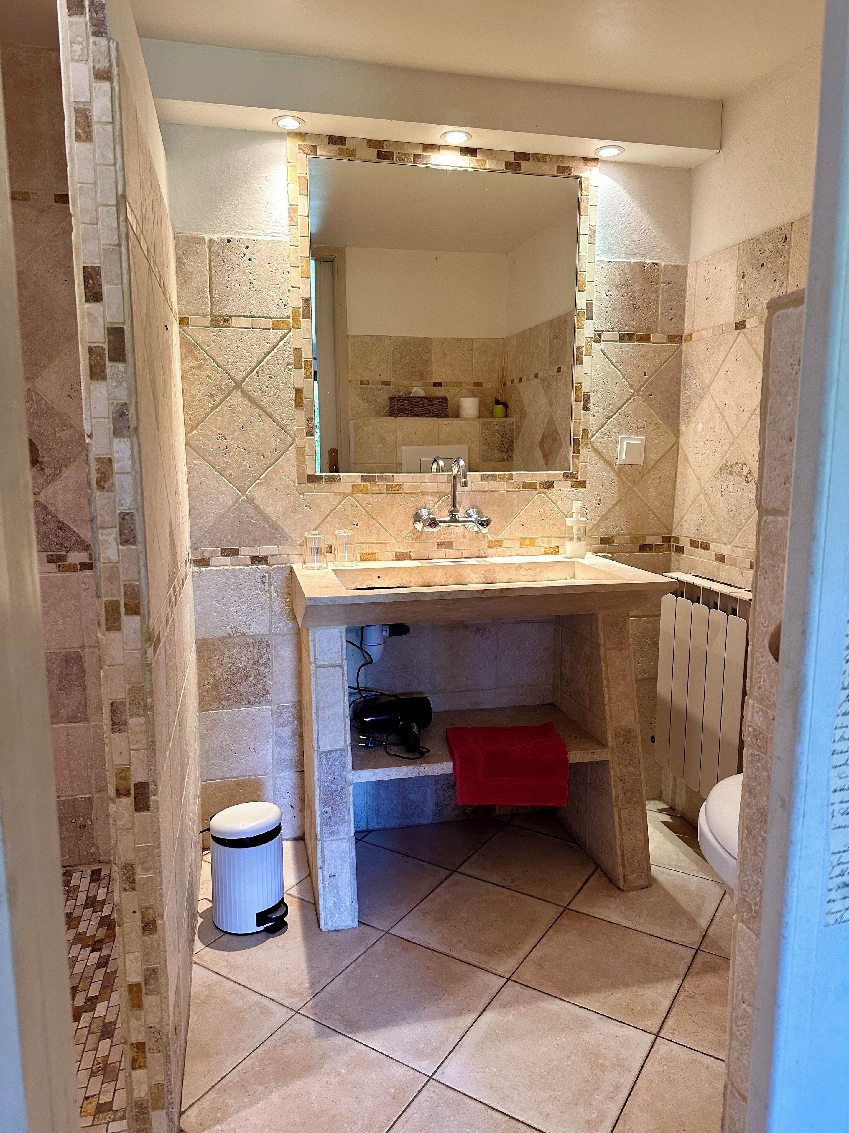 A bathroom with a tiled floor, a sink with a mirror above it, and a toilet.