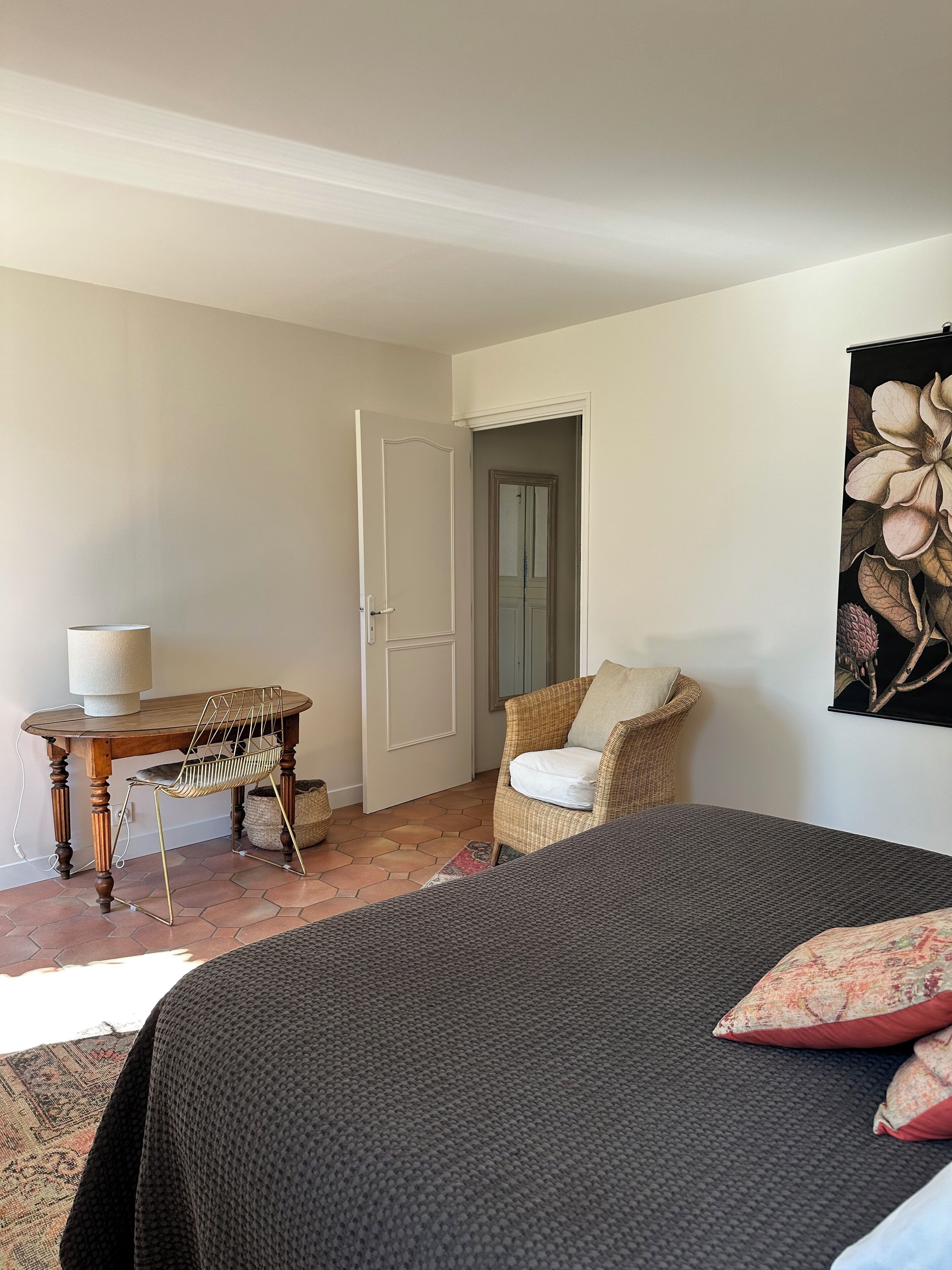 Un dormitorio con cama, una silla, una mesa y una puerta.
