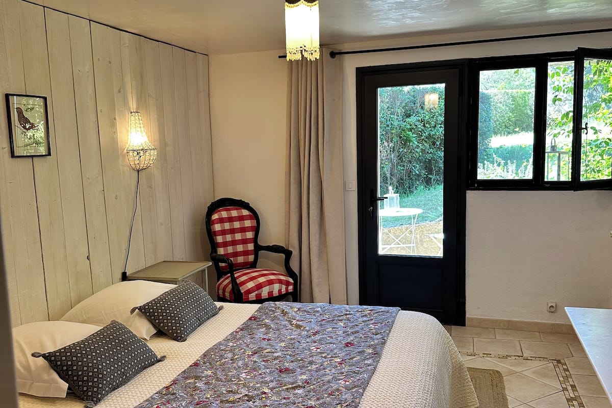 A bedroom with a bed, a chair, a window, and a door.