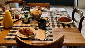 A dining table with breakfast items, a view of a garden through a large arched window. - Bergerie de Beaudine (Forcalquier)