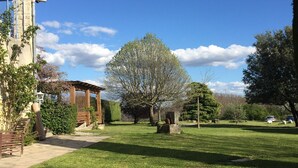 A well-maintained lawn with a wooden pergola, stone structures, and a variety of trees. - Bergerie de Beaudine (Forcalquier)
