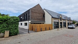 Un bâtiment moderne doté d’un toit en pente, d’une clôture en bois et d’une allée pavée.