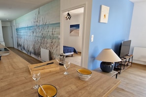 A modern living room with a wooden coffee table, a lamp, and a painting of a beach scene.