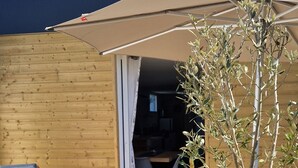 Une terrasse extérieure avec une table et des chaises, un mur en bois et un espace abrité.