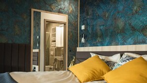 A bedroom with a bed, two mustard-colored pillows, a wooden headboard, and a mirror above the bed. - La Siesta (Markovci)