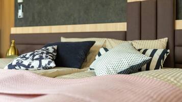 A hotel room with a bed featuring multiple pillows and a headboard with a wooden and fabric design.
