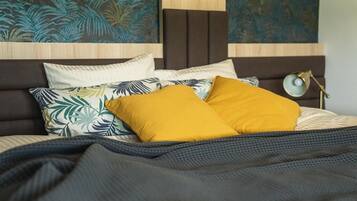 Una cama con cabecera, varias almohadas y una colcha.