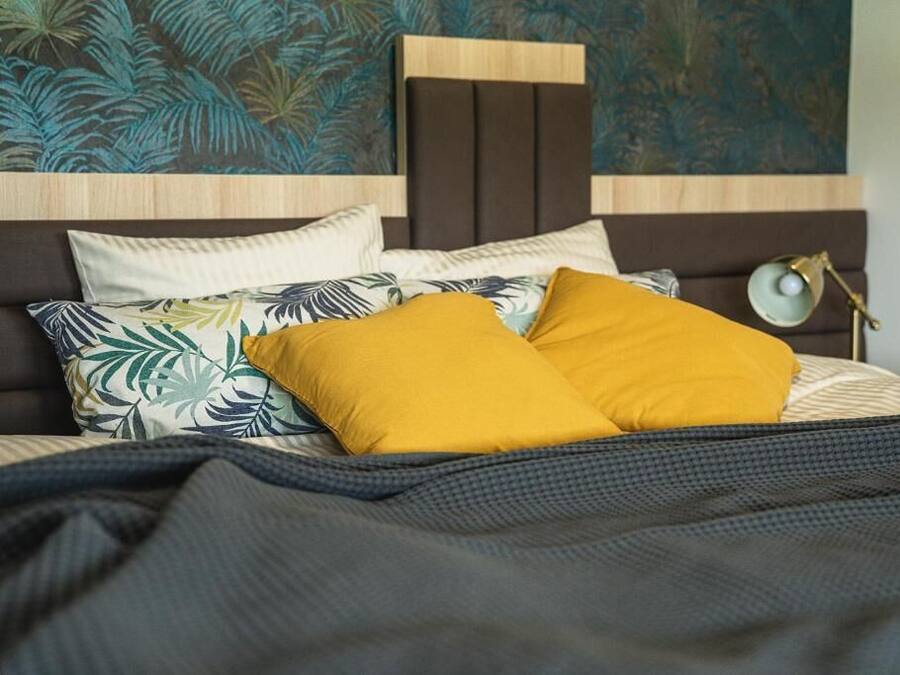 Una cama con cabecera, varias almohadas y una colcha.