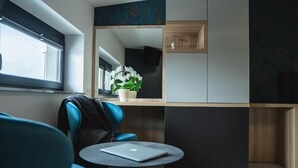 A modern room with a sofa, a small round table with a laptop, a window, and a decorative plant. - La Siesta (Markovci)