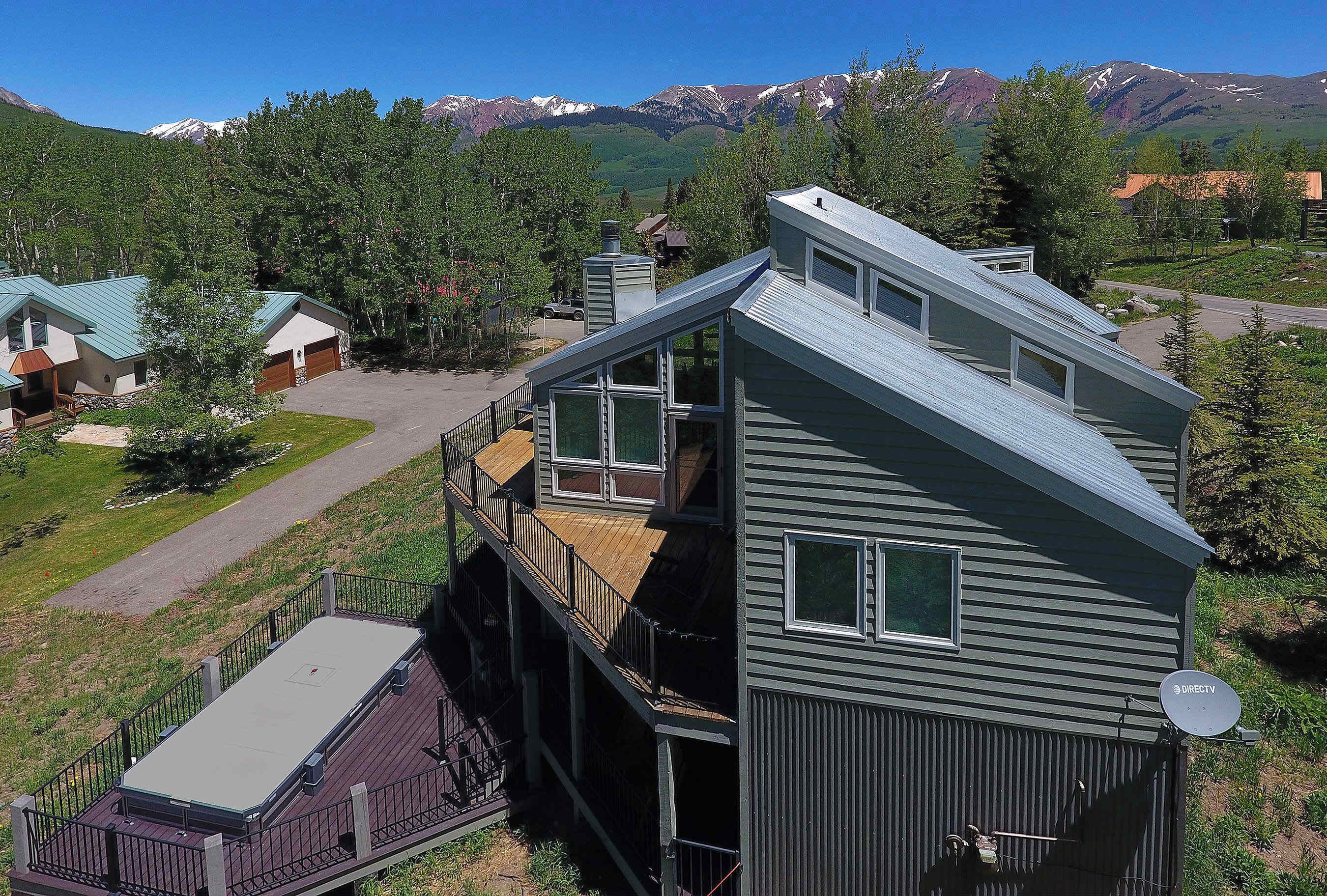 A multi-story building with a flat roof, satellite dish, and a view of mountains.