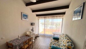 Ein gemütlicher Wohnbereich mit Esstisch, Stühlen, einer Couch und einem Deckenventilator.